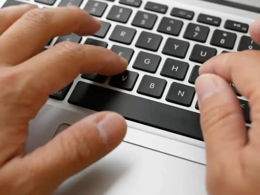 Kädet tietokoneen näppäimistöllä.